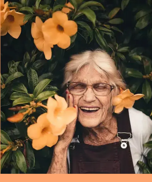 Seniorin zwischen gelben Blumen aus dem München-Flyer von VitaTop Pflege